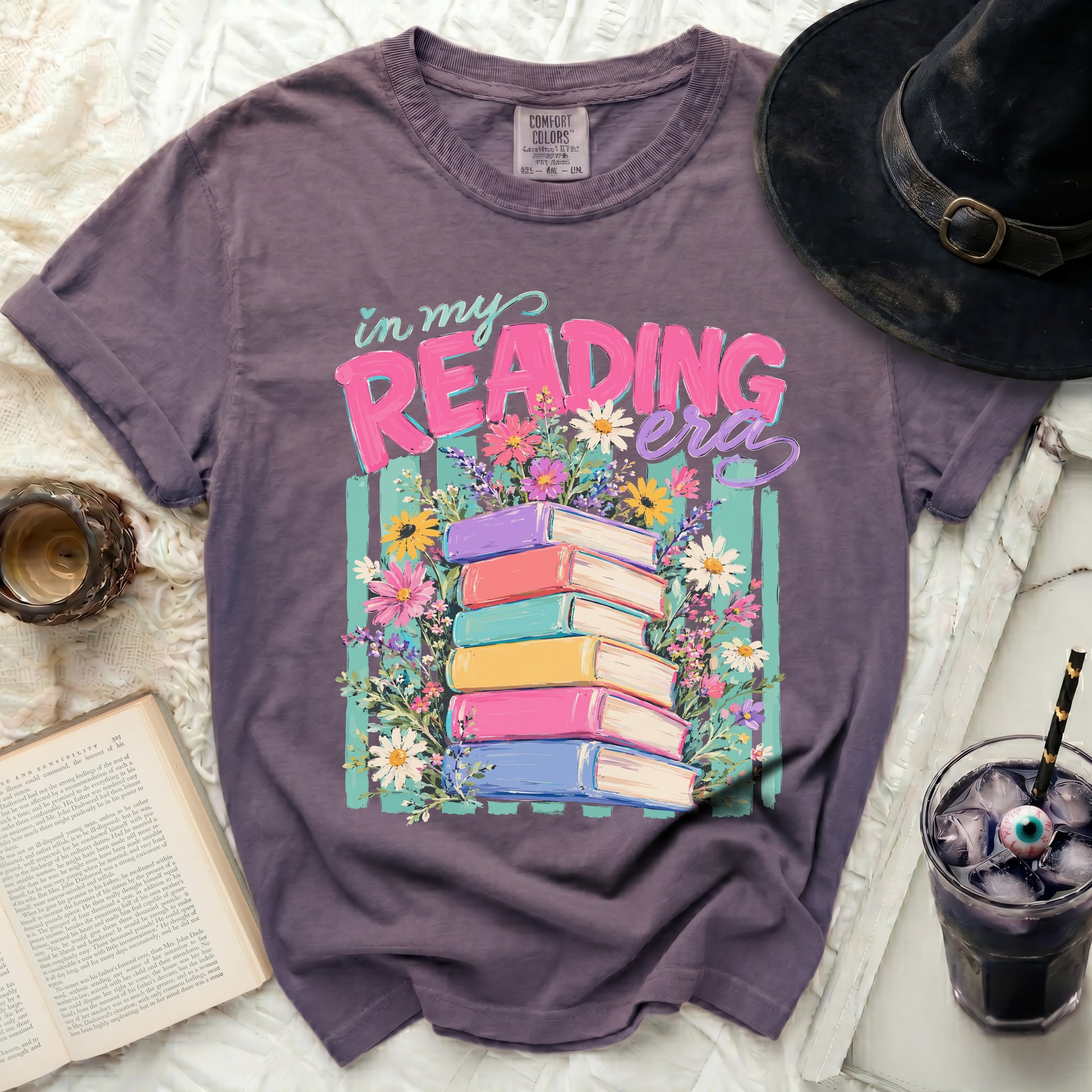 T-shirt with "in my READING era" text and stack of books with flowers.