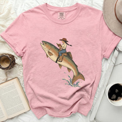 Pink t-shirt with illustration of cowgirl riding a jumping fish.