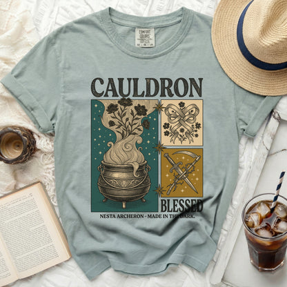 Green t-shirt with "CAULDRON BLESSED NESTA ARCHERON MADE IN THE DARK" graphic.