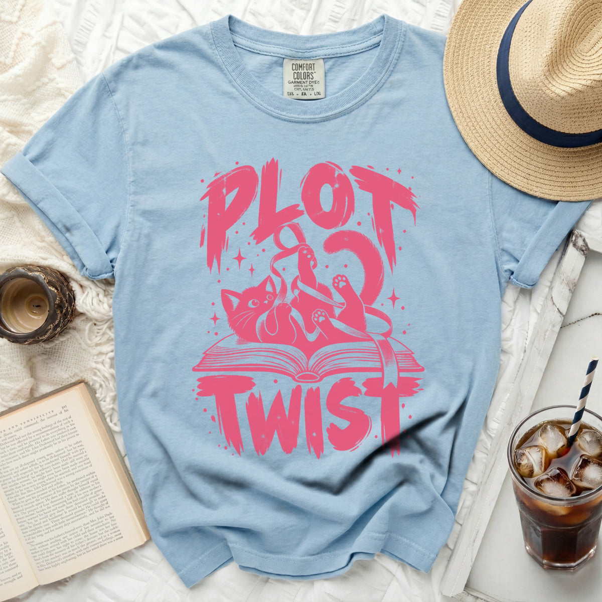 Light blue t-shirt with pink "PLOT TWIST" text and a cat on a book graphic.