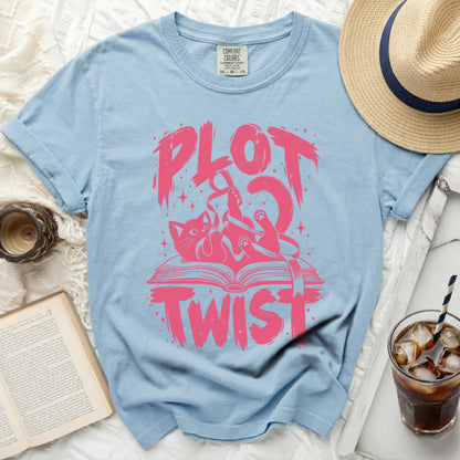 Light blue t-shirt with pink "PLOT TWIST" text and a cat on a book graphic.