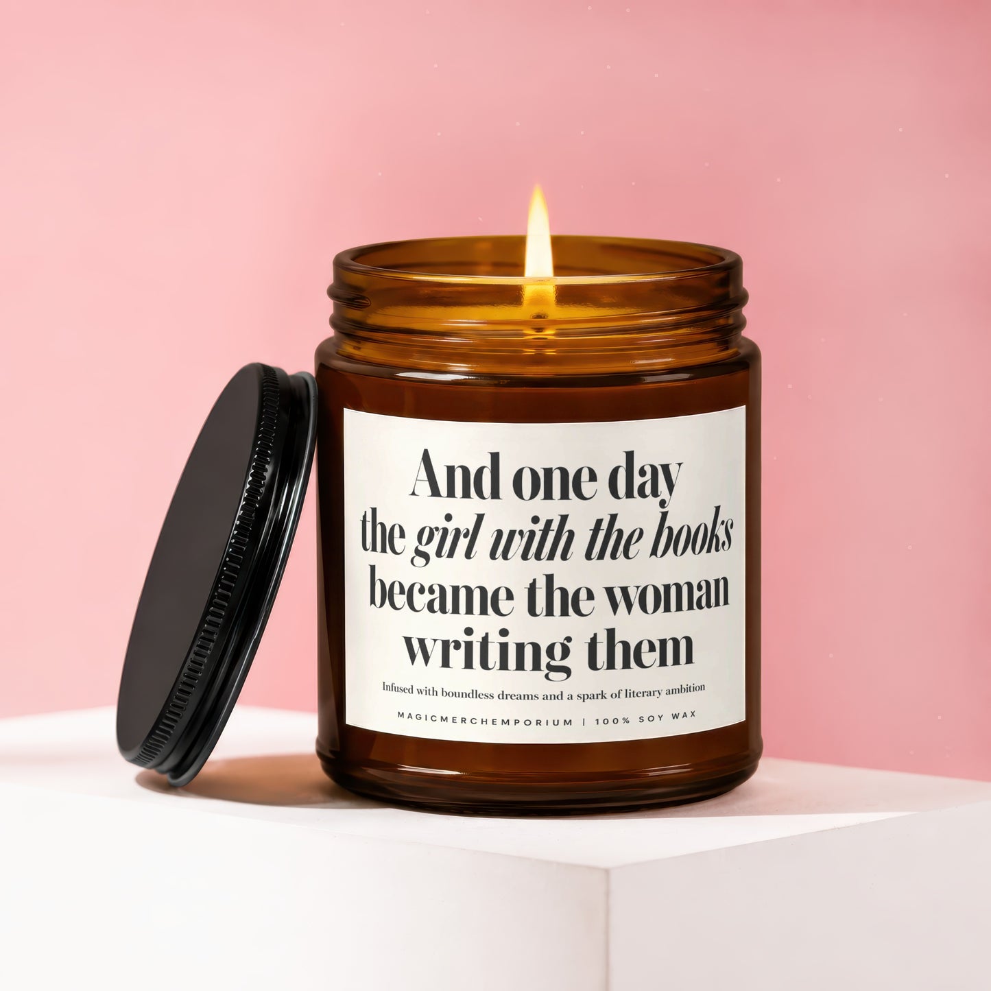 Amber glass candle with lit wick, features text about girls with books becoming writers.