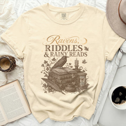 Ravens, Riddles & Rainy Reads graphic on a cream t-shirt.