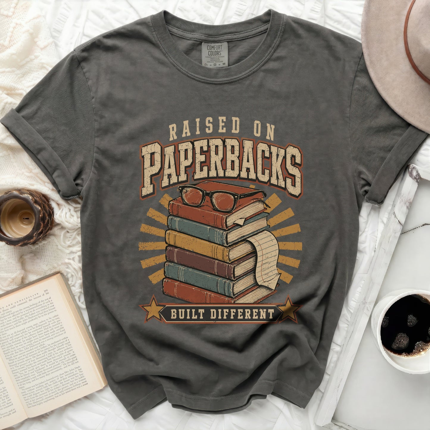 Raised on Paperbacks Built Different t-shirt with stack of books and glasses.