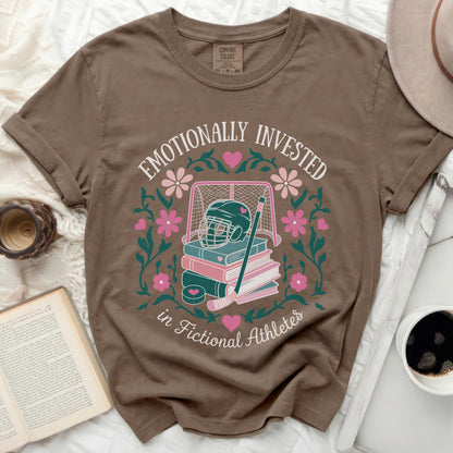Brown t-shirt with "Emotionally Invested in Fictional Athletes" text and book illustration.
