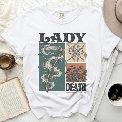 White t-shirt with "LADY DEATH" graphic, scythe, swords, and floral designs.