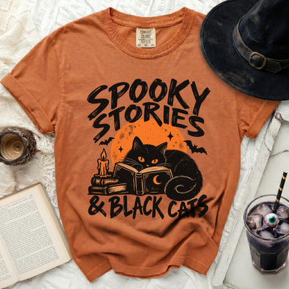 Orange t-shirt with "Spooky Stories & Black Cats" text, a black cat reading, and a candle.