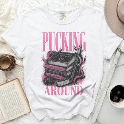 White t-shirt with "PUCKING AROUND" and book graphics.