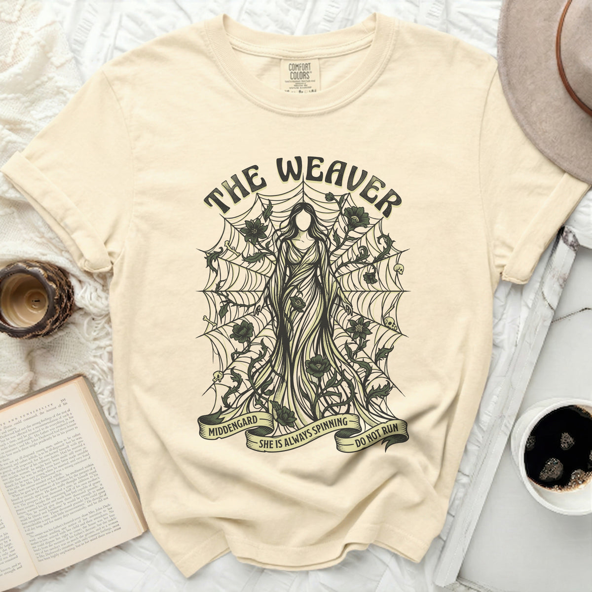 The Weaver t-shirt features a skeletal figure on a spiderweb with text reading "MIDDENGARD SHE IS ALWAYS SPINNING DO NOT RUN".