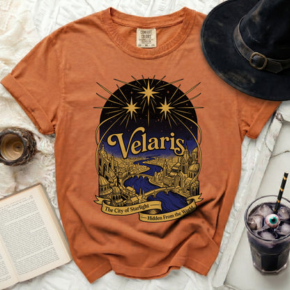 Orange t-shirt with a graphic of Velaris, the City of Starlight, hidden from the world.