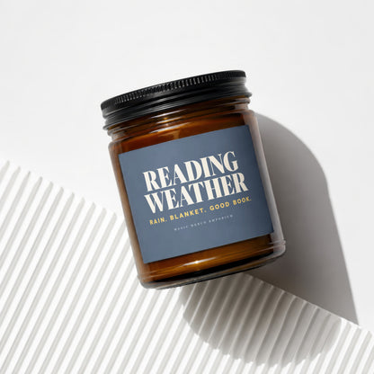 Amber jar candle with dark label reading "Reading Weather".