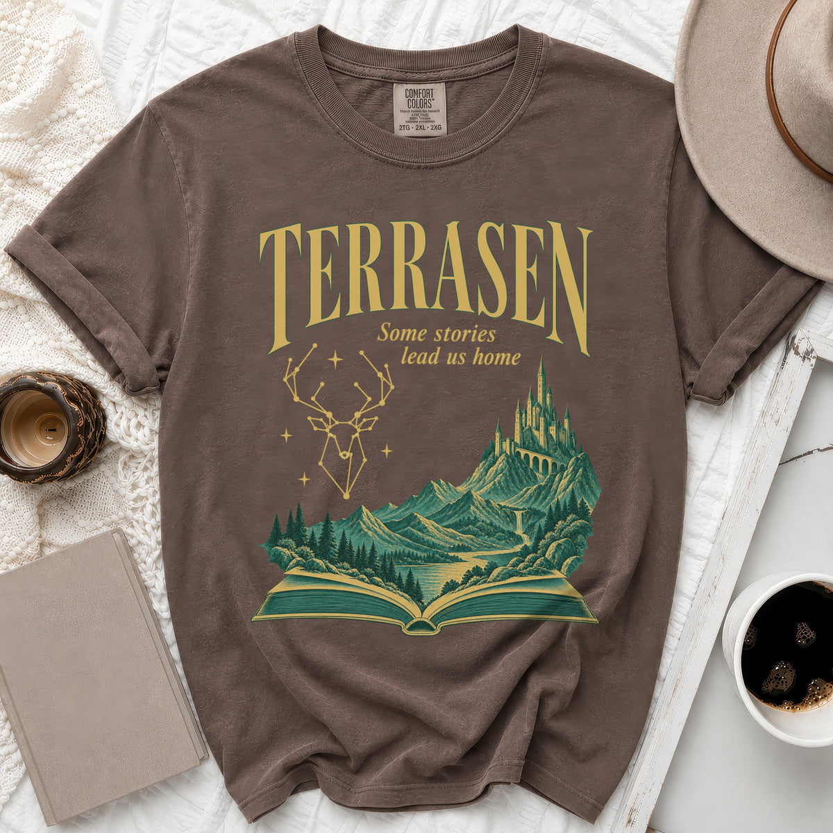 Brown t-shirt with "Terrasen Some stories lead us home" text and fantasy scene.