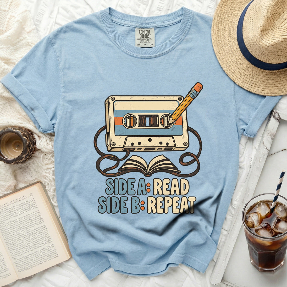 Light blue t-shirt graphic with cassette tape, pencil, and open book, saying "Side A: Read, Side B: Repeat".