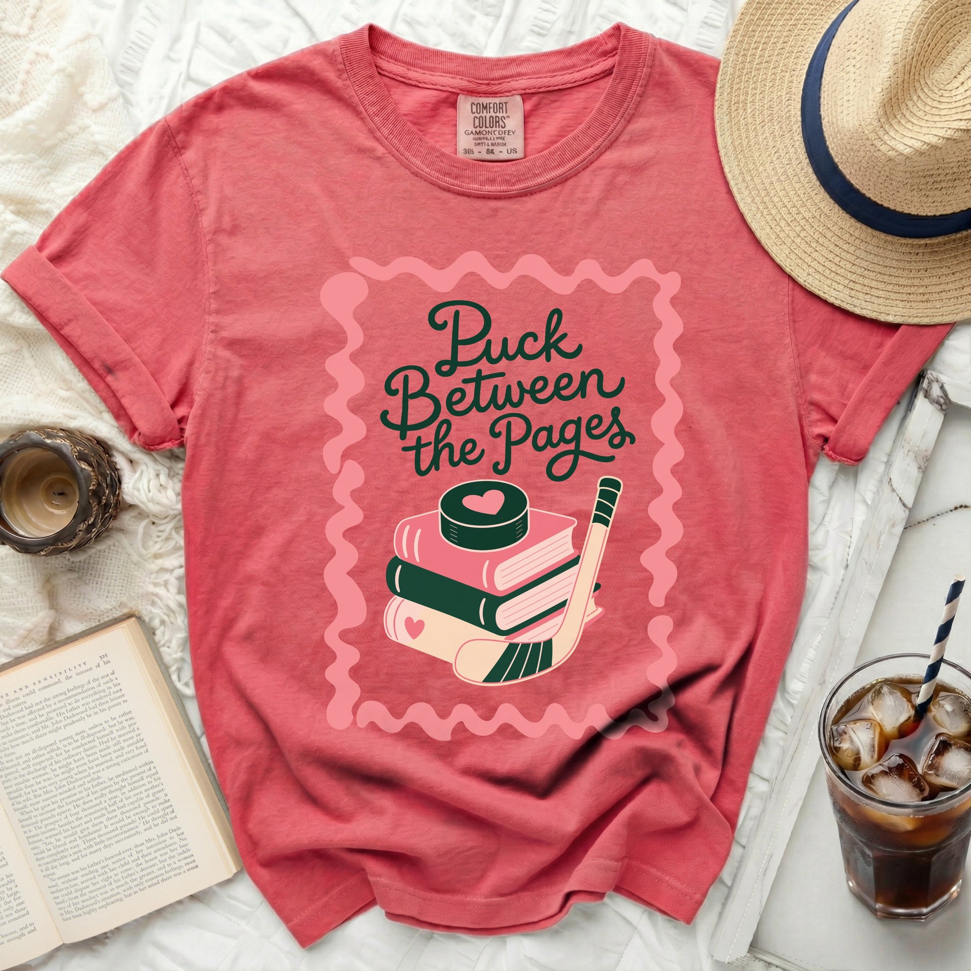 Pink t-shirt with stacked books, hockey puck, and stick graphic.