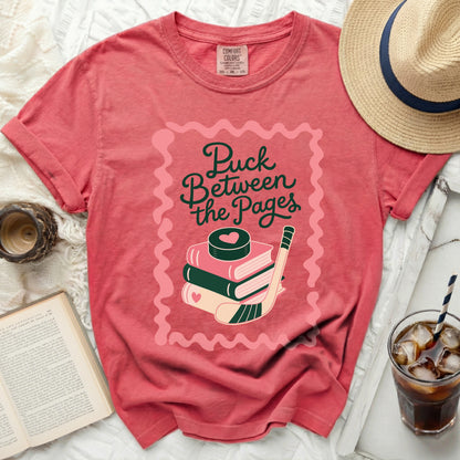 Pink t-shirt with stacked books, hockey puck, and stick graphic.