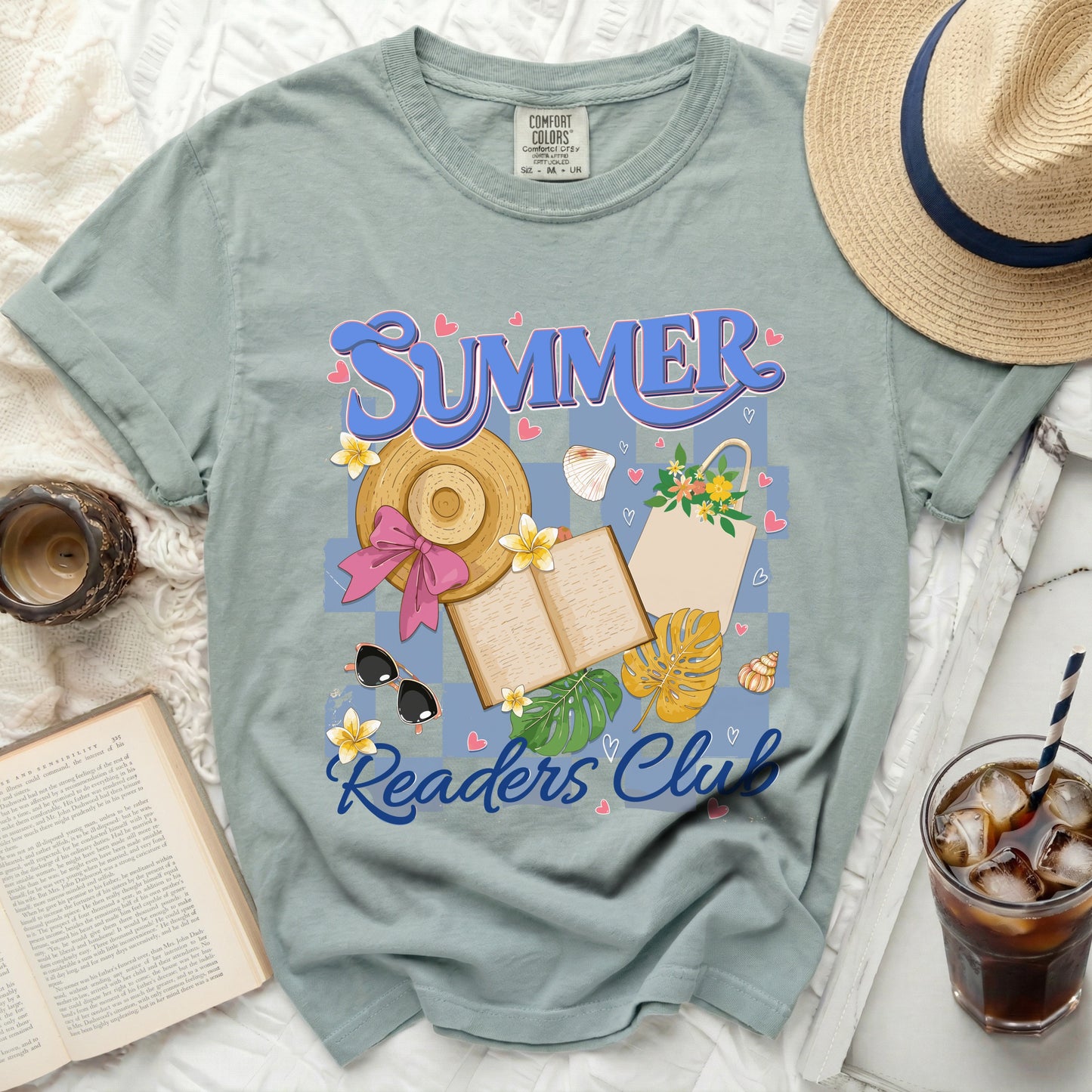 "Summer Readers Club" graphic on a sage green t-shirt with beach accessories and an open book.