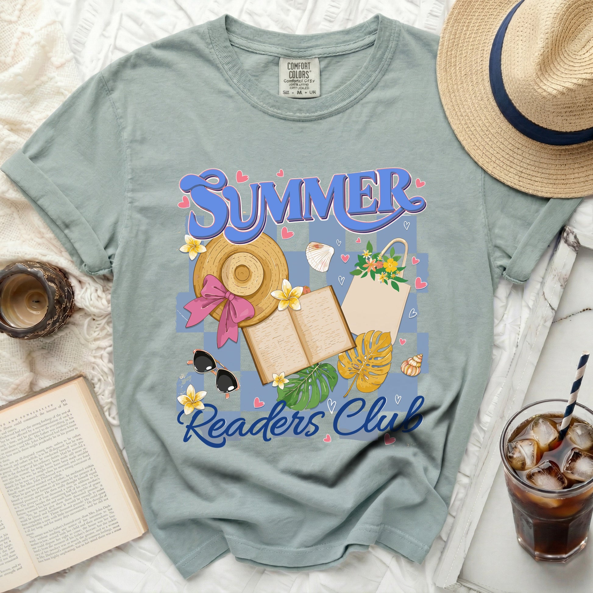 "Summer Readers Club" graphic on a sage green t-shirt with beach accessories and an open book.