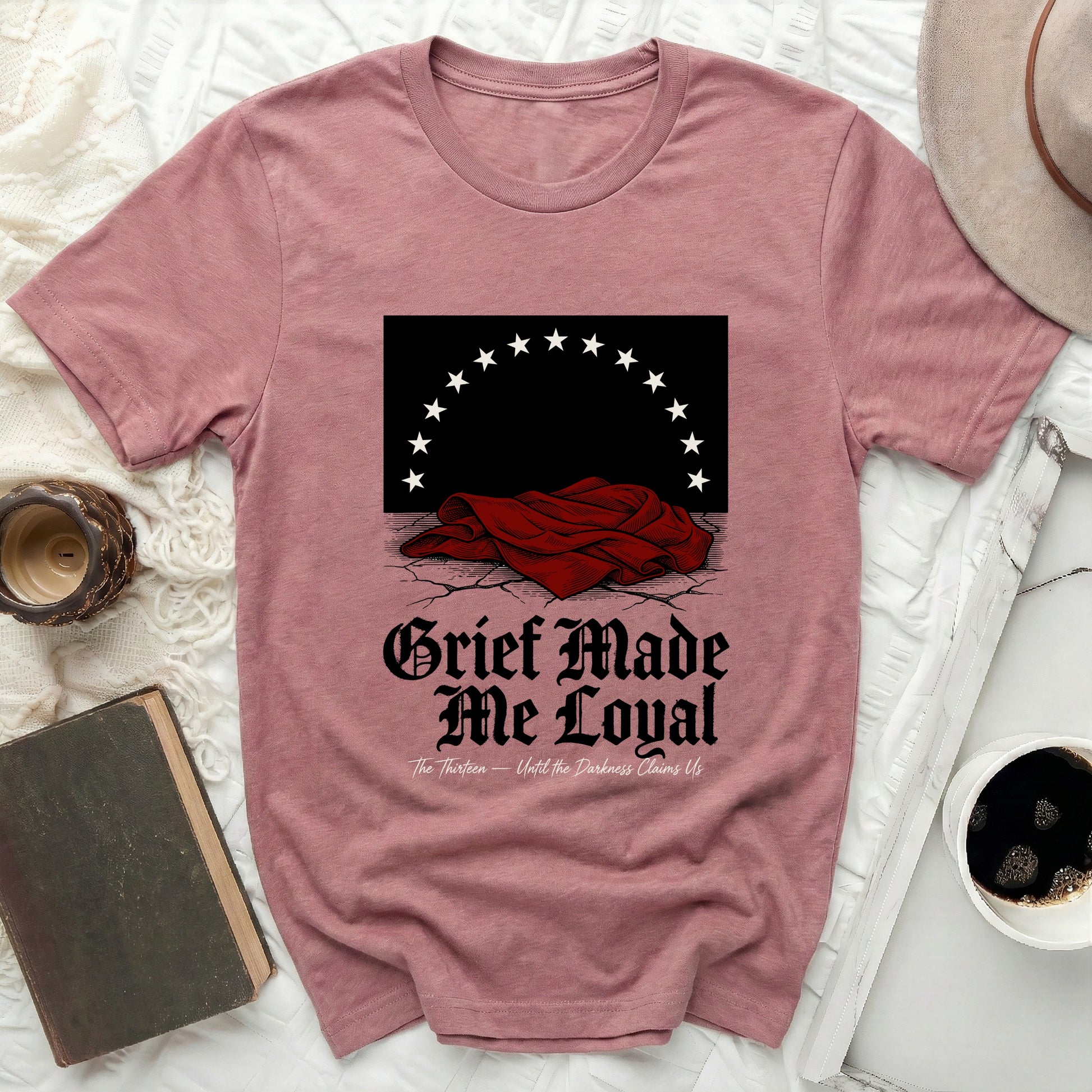 Dark graphic on pink t-shirt with stars and "Grief Made Me Loyal" text.