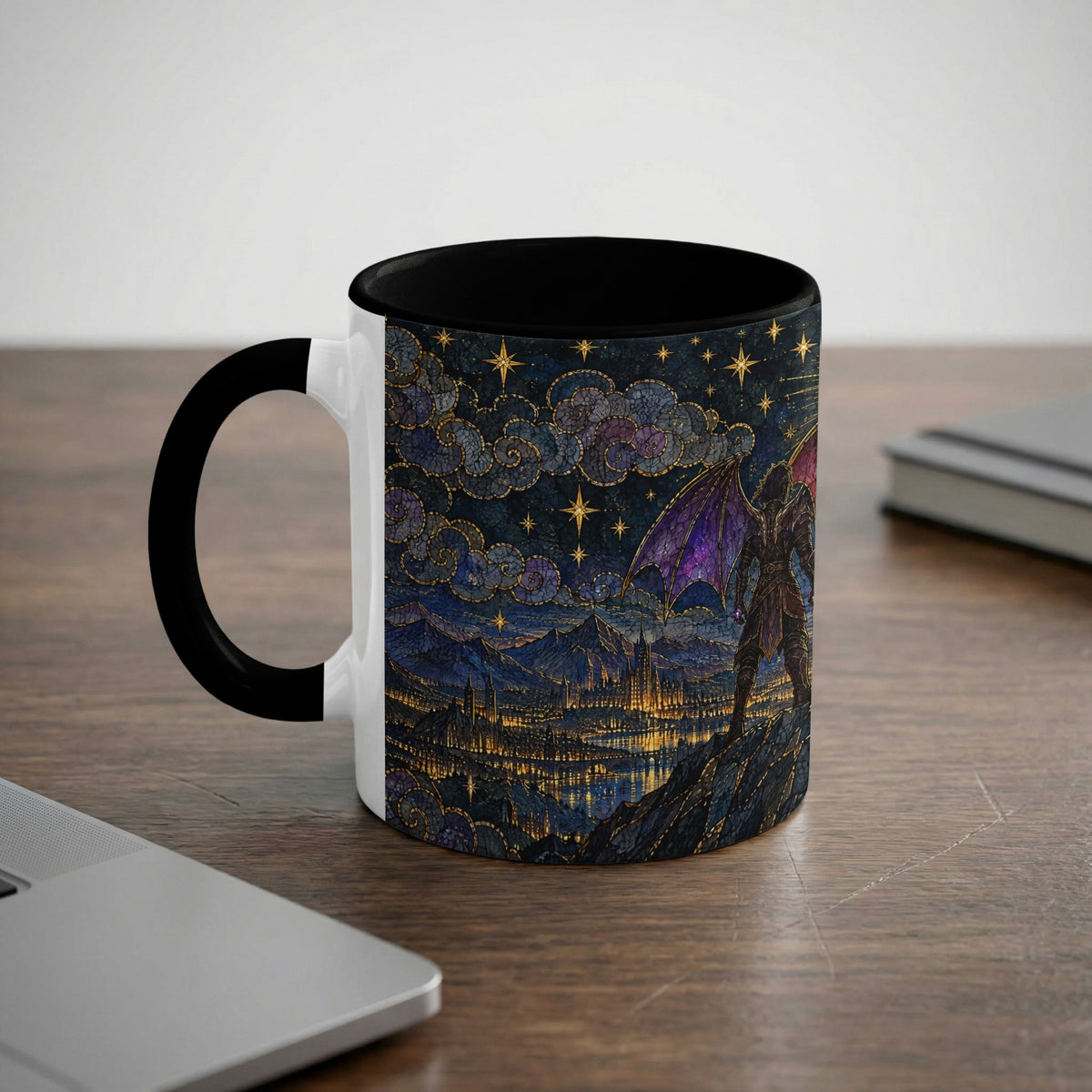 A white ceramic mug with a black handle and rim, featuring a fantasy mosaic design of a winged figure overlooking a city beneath a starry night sky, sits on a wooden desk.
