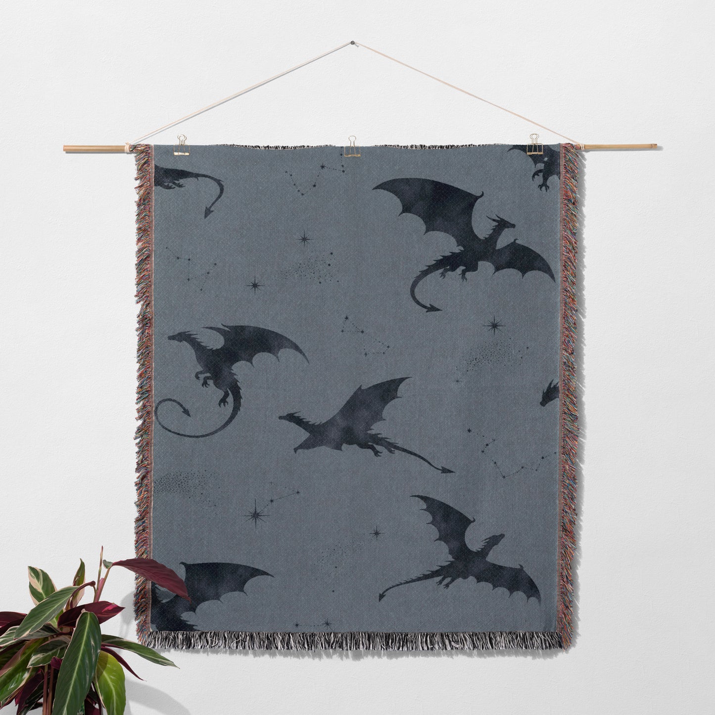 a gray blanket with black dragon silhouettes on it, hanging on a wall.