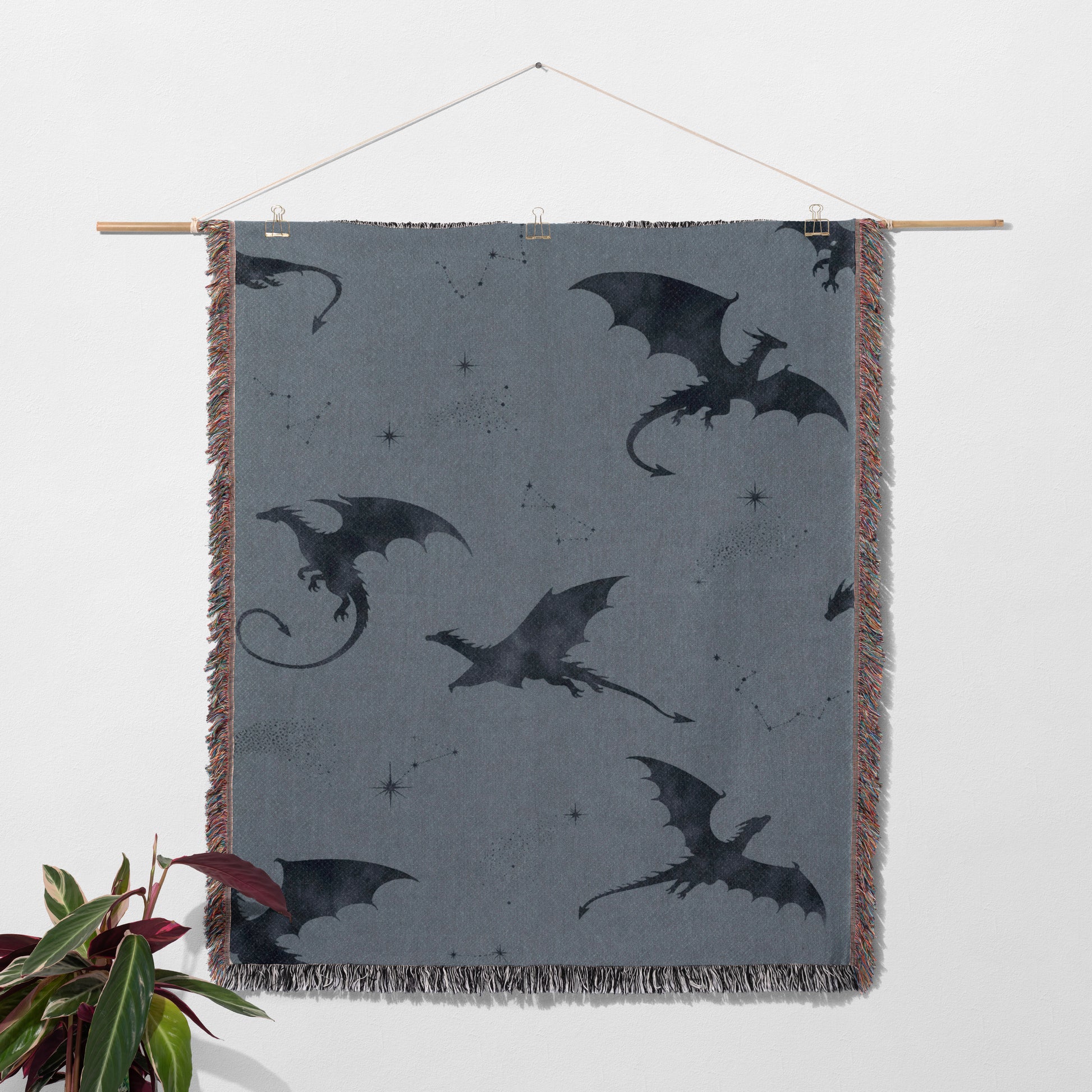 a gray blanket with black dragon silhouettes on it, hanging on a wall.