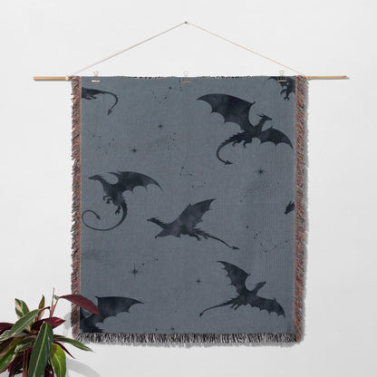 a gray blanket with black dragon silhouettes on it, hanging on a wall.