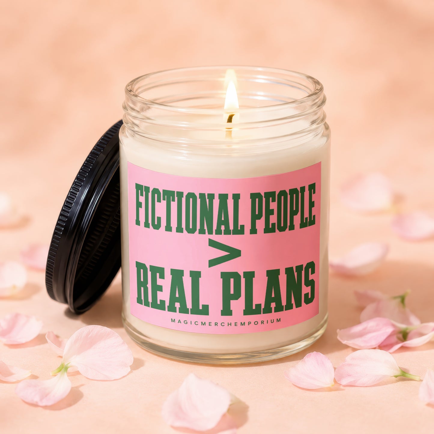 Glass candle with pink label reading "Fictional People > Real Plans" surrounded by petals.