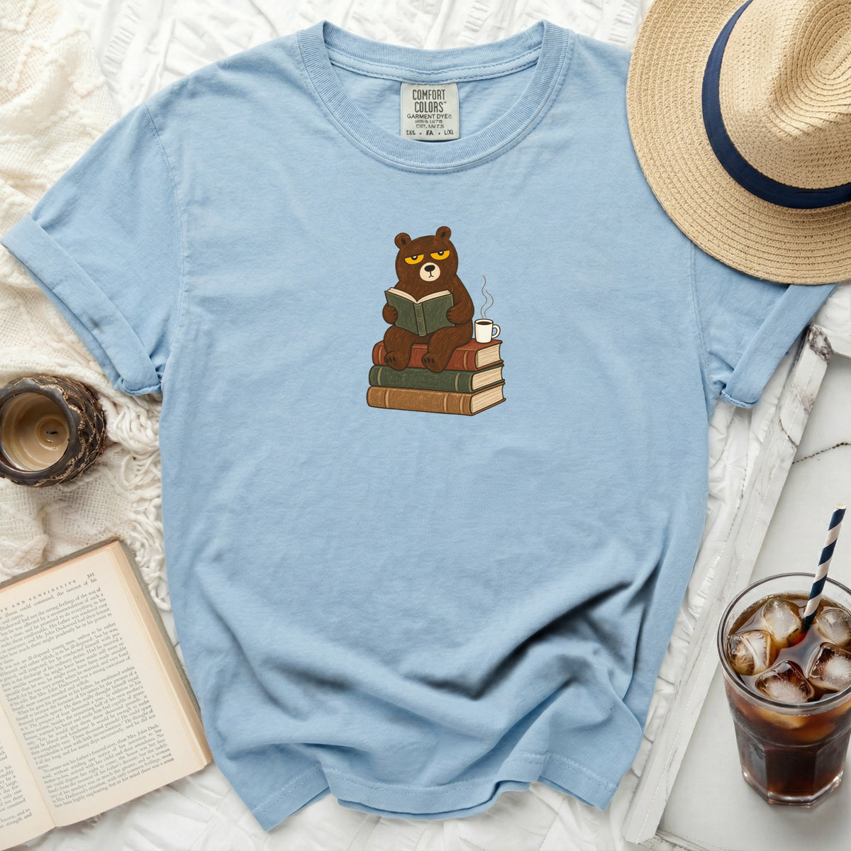 Blue t-shirt with a cartoon bear reading on stacked books, "Comfort Colors" label visible.