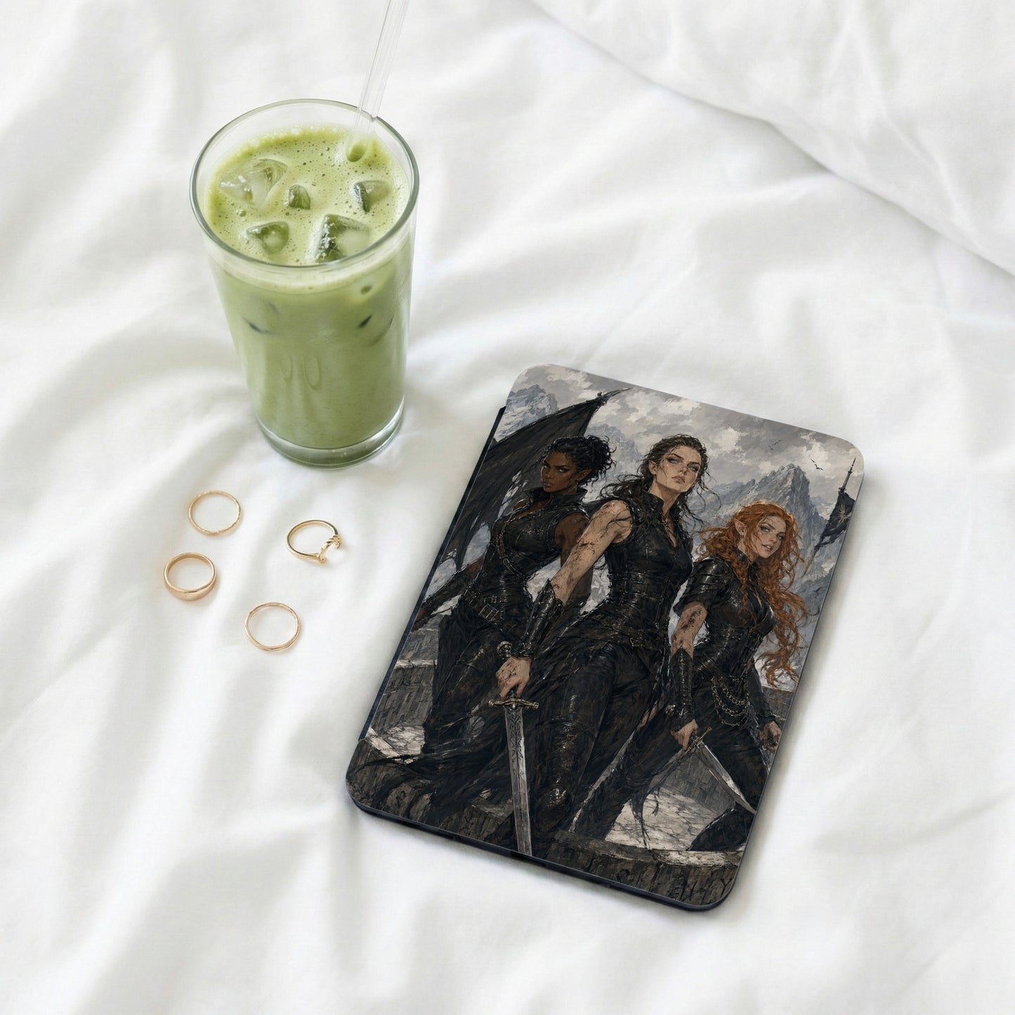 Three women in dark armor with swords stand before a mountain landscape on a tablet.