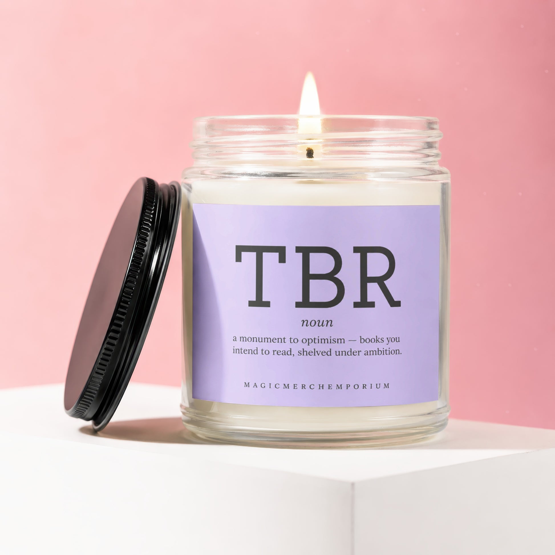 Candle with "TBR" definition label and lit wick on pink background.