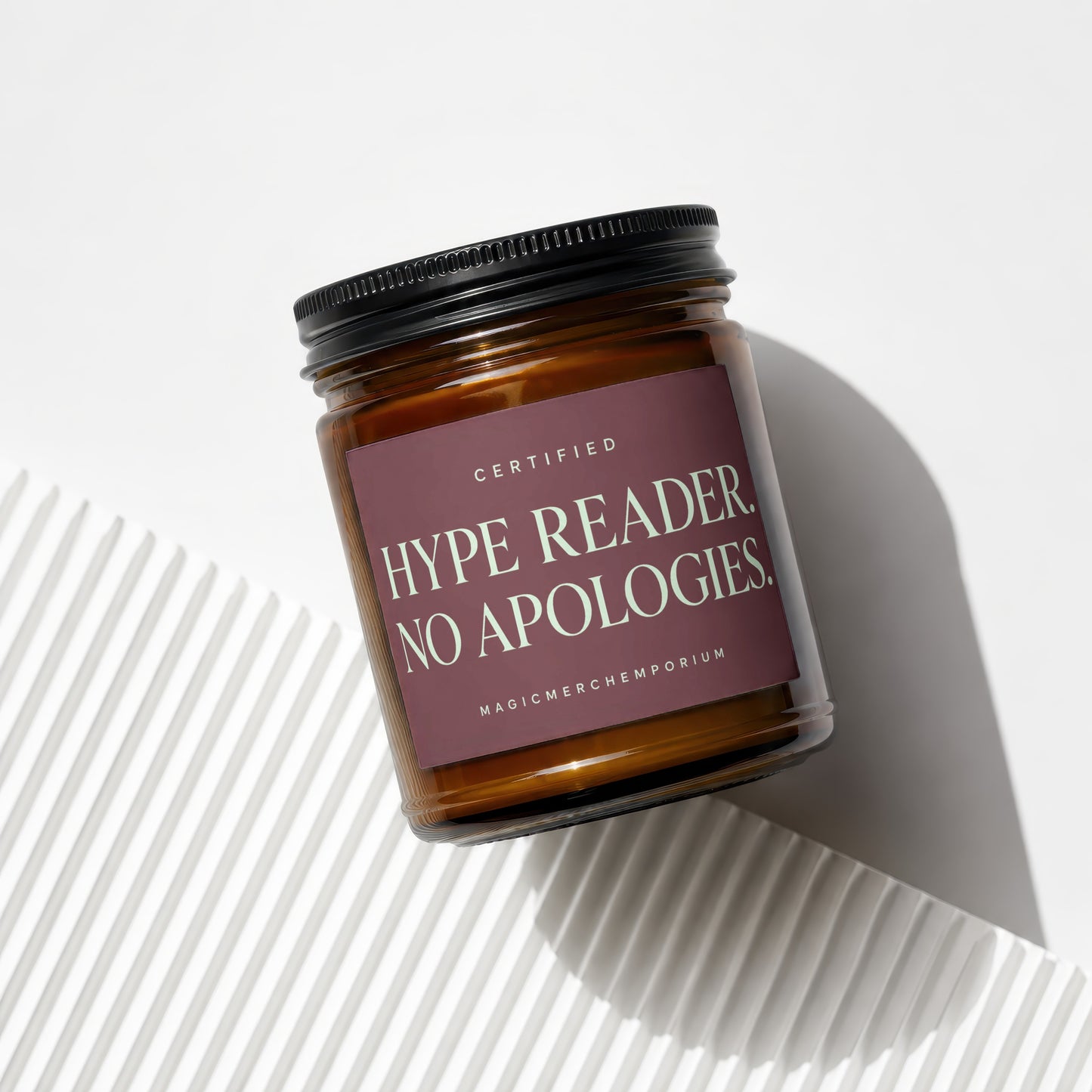 Amber glass candle with a dark label reading "CERTIFIED HYPE READER. NO APOLOGIES."