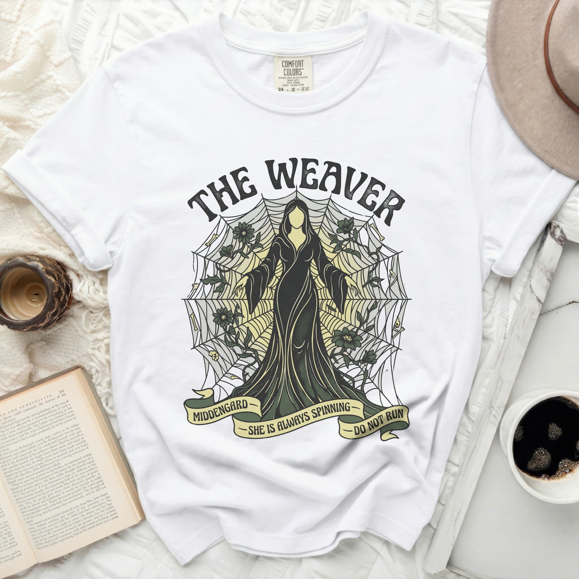 White t-shirt with "The Weaver" design, featuring a robed figure and spiderweb.