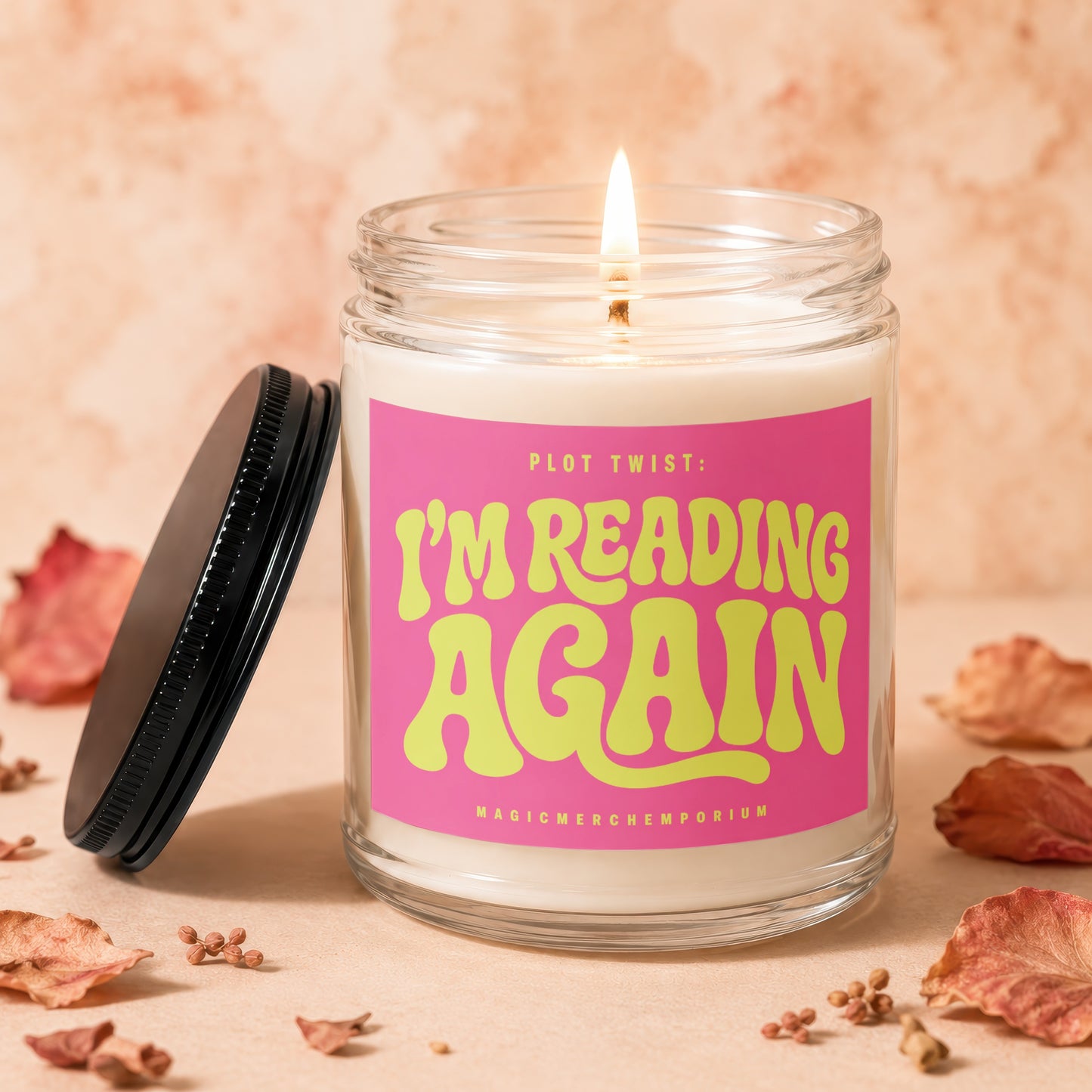 Burning candle in glass jar with pink label reading "Plot Twist: I'm Reading Again".