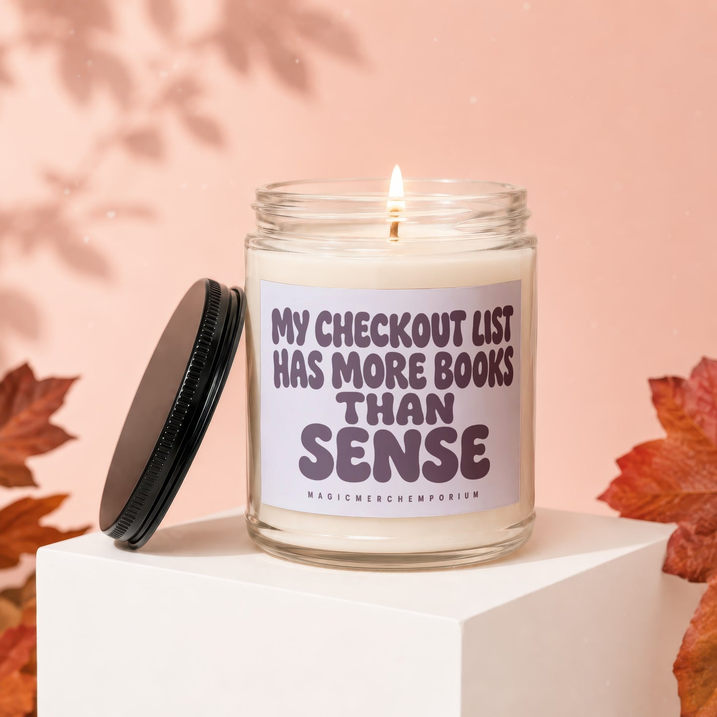 Jar candle with lit wick and label that reads "My Checkout List Has More Books Than Sense."