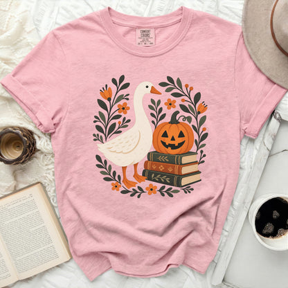 Pink t-shirt with a white goose, pumpkin, and books graphic.
