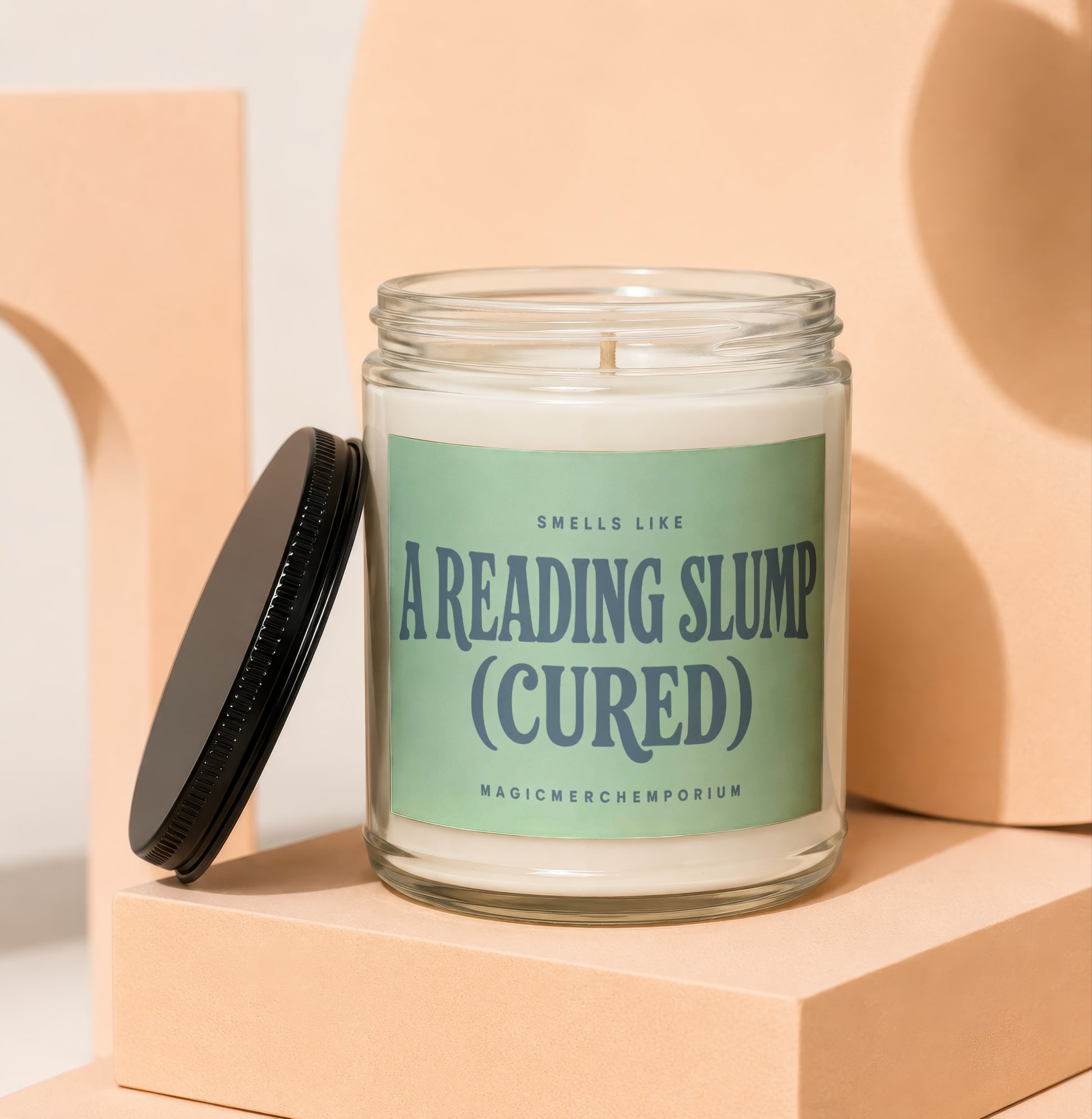 Glass jar candle with a green label reading: "Smells like a reading slump (cured)".