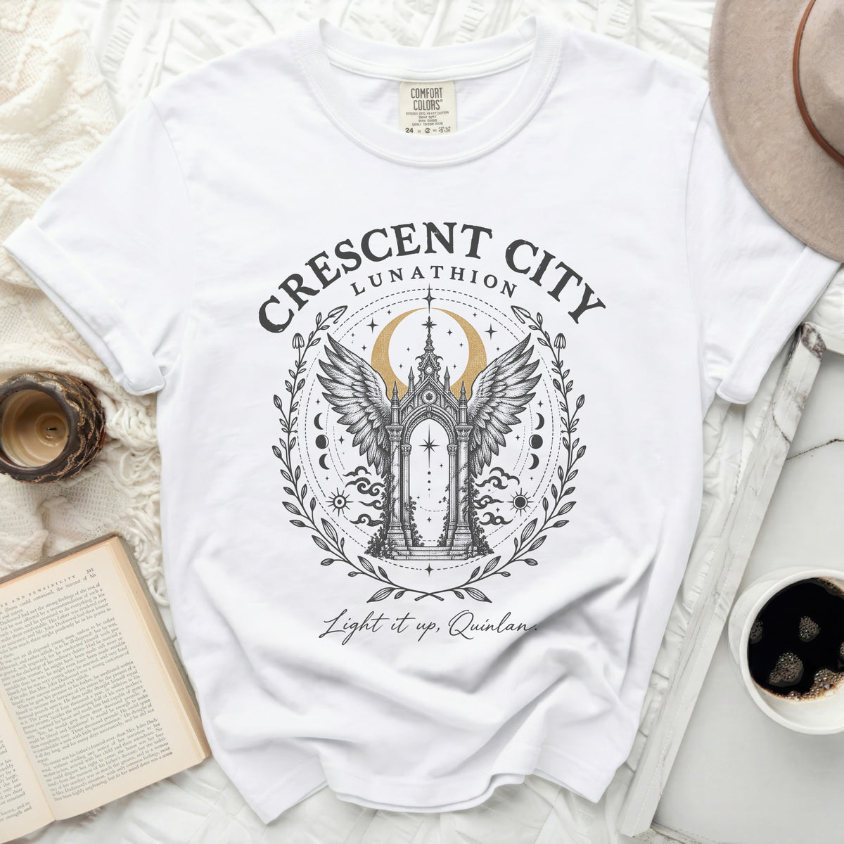White Comfort Colors t-shirt featuring a Crescent City Lunathion graphic with an arched gateway, wings, crescent moon, and text.