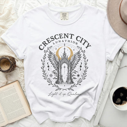 White Comfort Colors t-shirt featuring a Crescent City Lunathion graphic with an arched gateway, wings, crescent moon, and text.