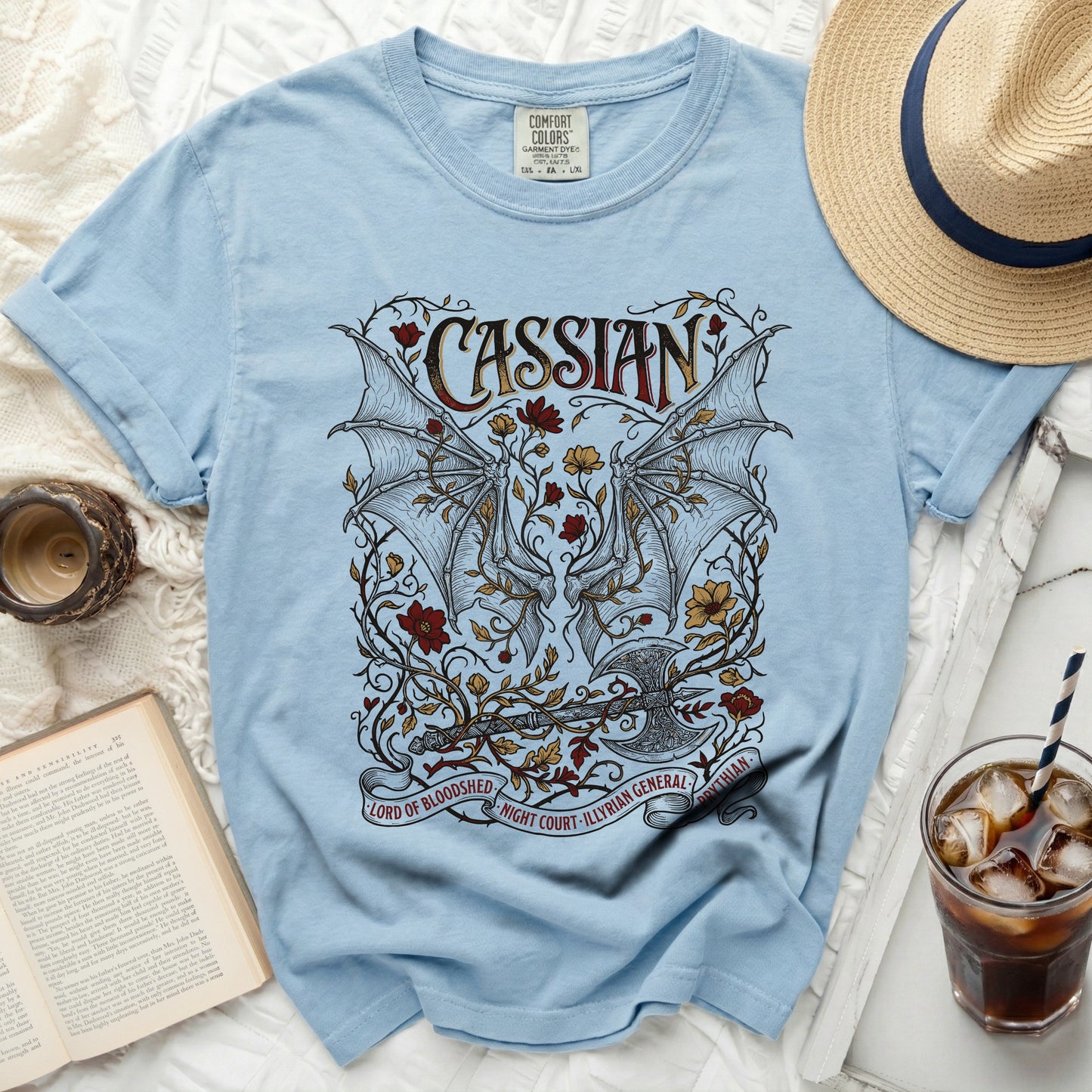 Light blue t-shirt with Cassian, wings, axe, and floral design.