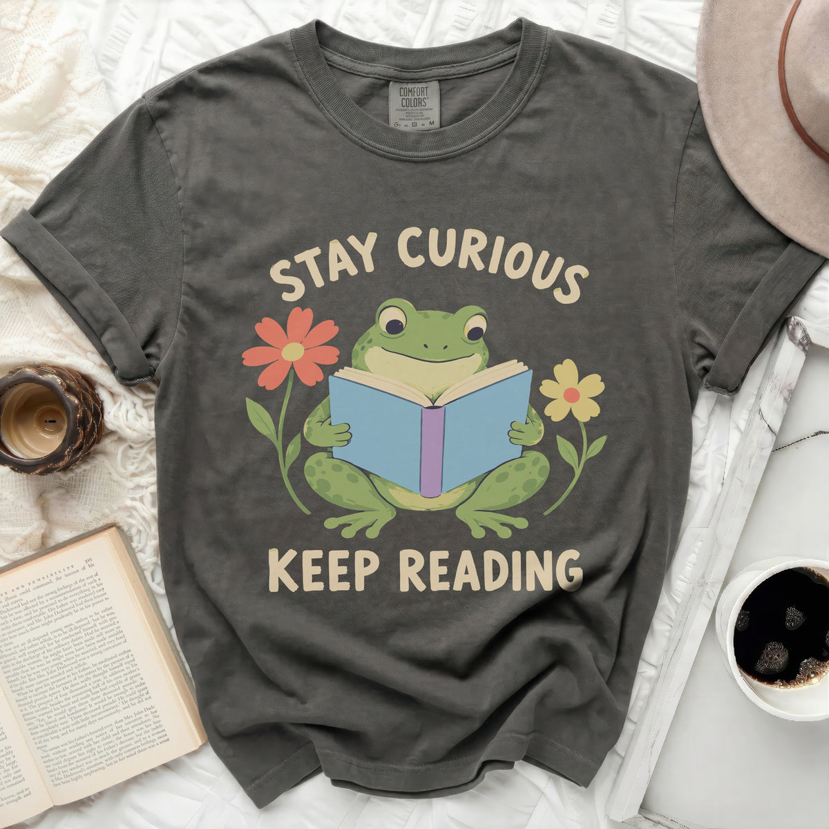 T-shirt with frog reading a book, "Stay Curious Keep Reading" text, and flowers.