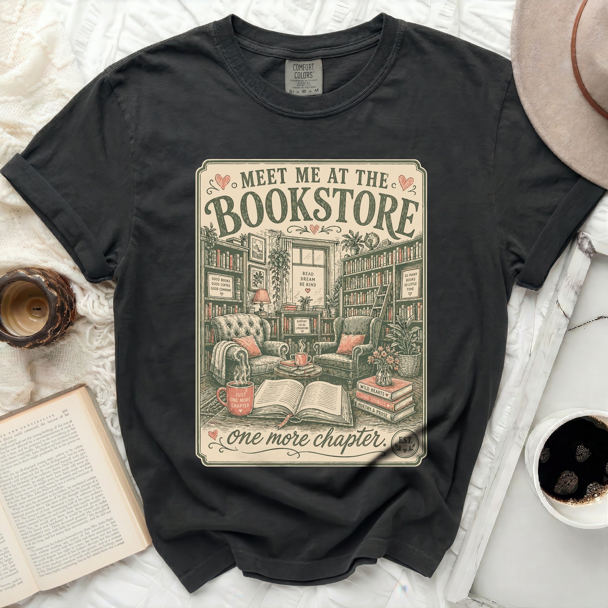 Dark t-shirt with "Meet Me at the Bookstore" graphic and cozy reading scene.