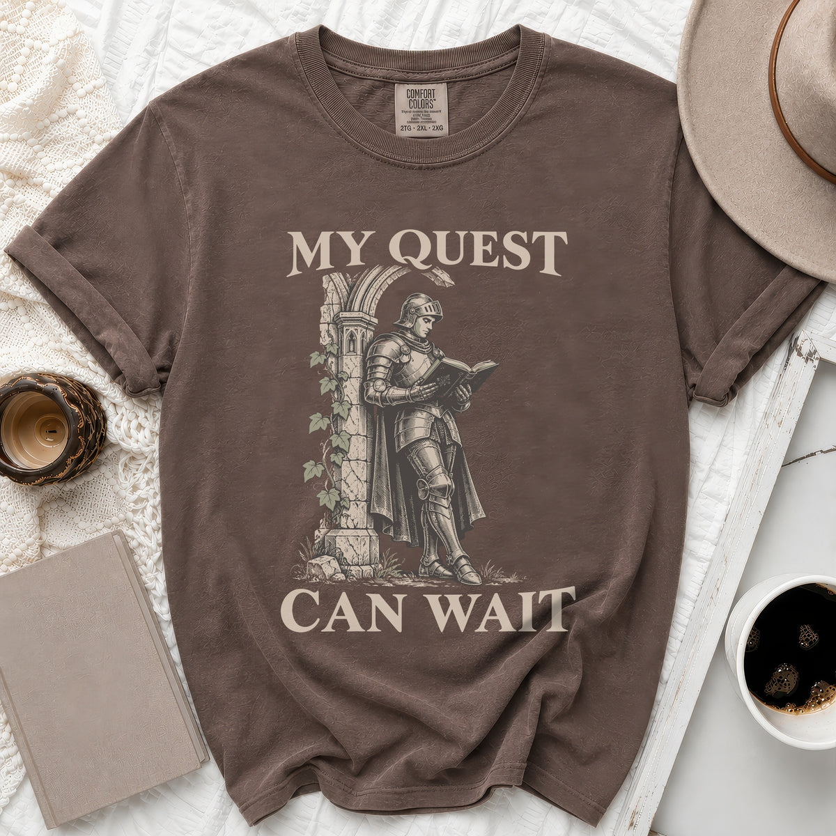 Brown t-shirt with knight reading a book, "MY QUEST CAN WAIT" text.