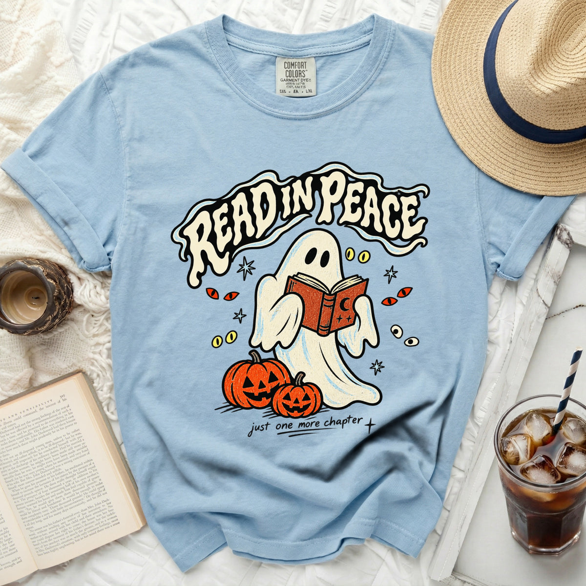 Light blue t-shirt with ghost reading a book, "Read in Peace" text and pumpkins.