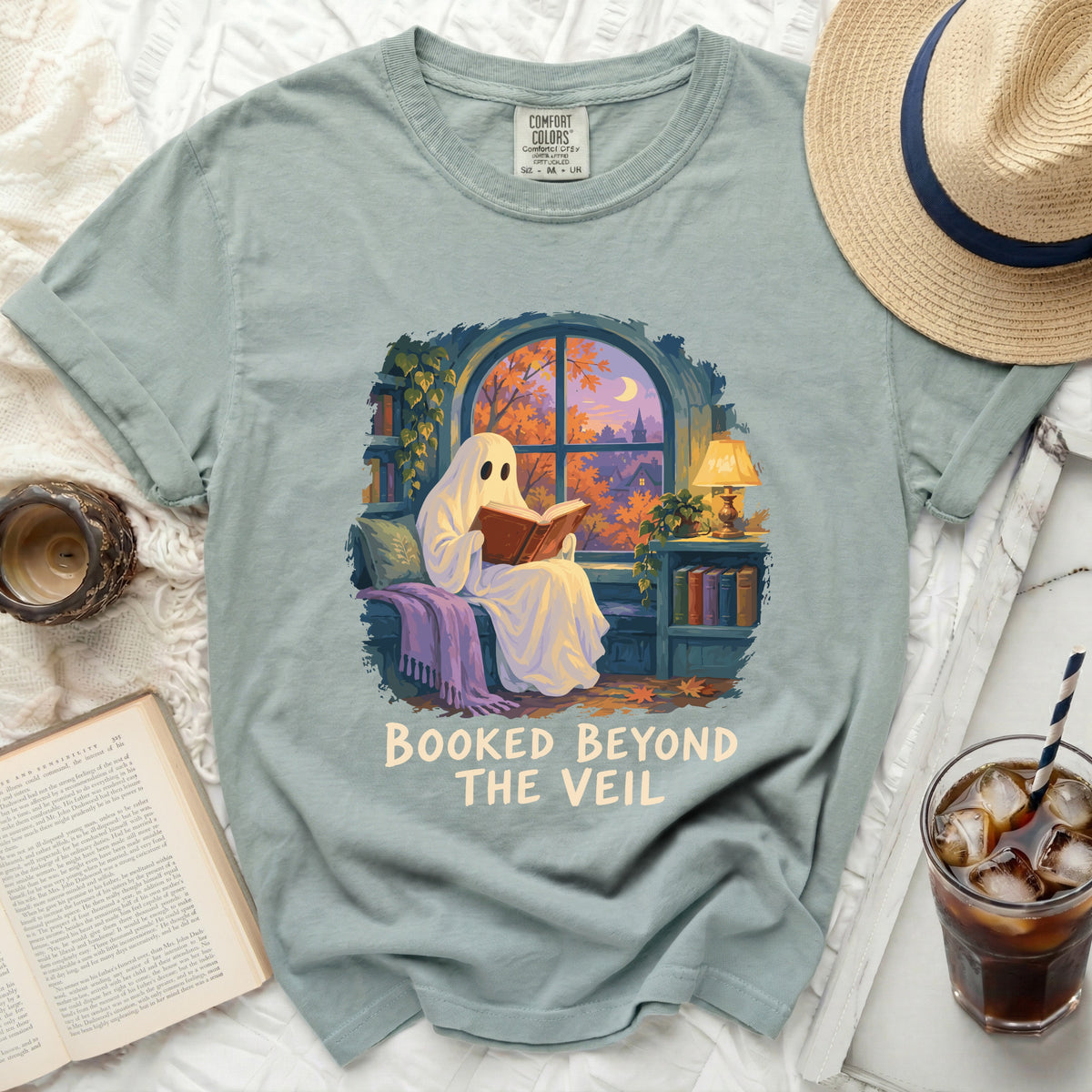 Ghost reading a book with text "Booked Beyond the Veil" on a t-shirt.
