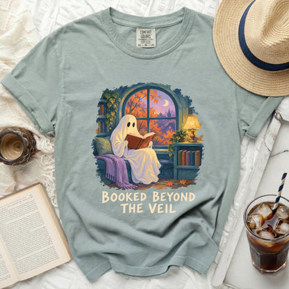 Ghost reading a book with text "Booked Beyond the Veil" on a t-shirt.