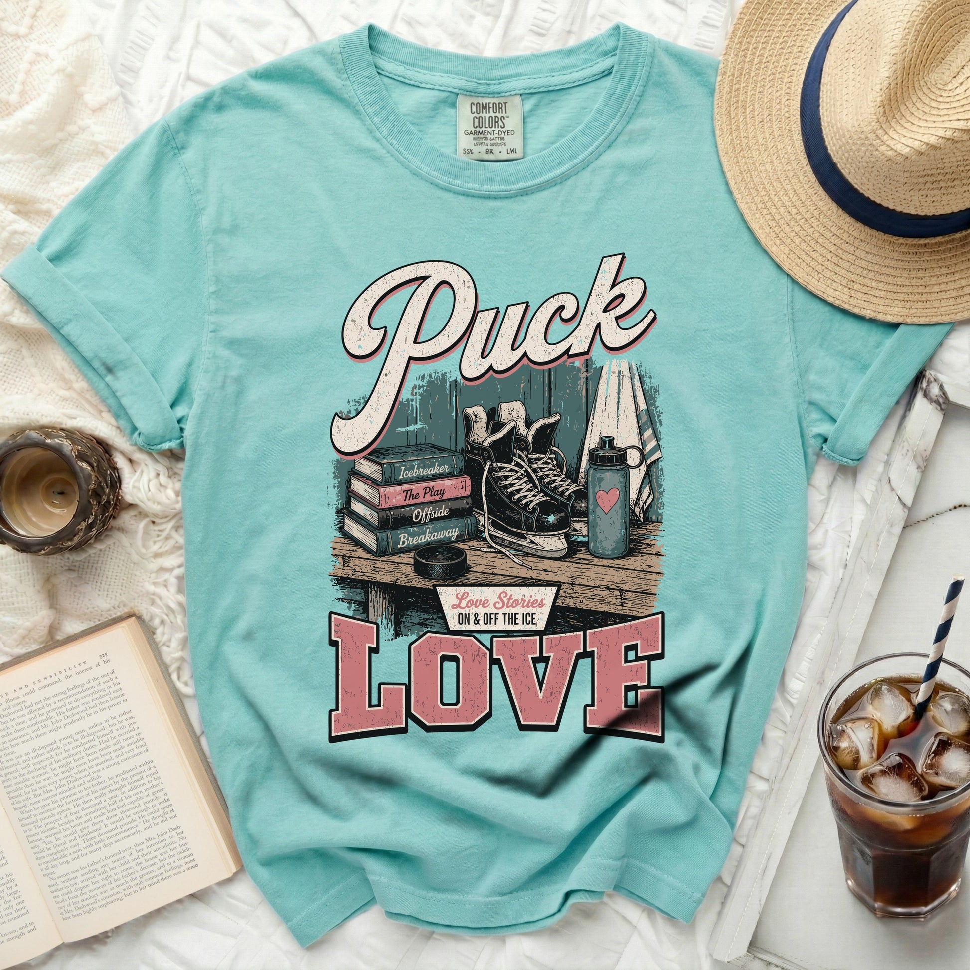Aqua t-shirt with "Puck Love" hockey graphic, book, and iced drink.