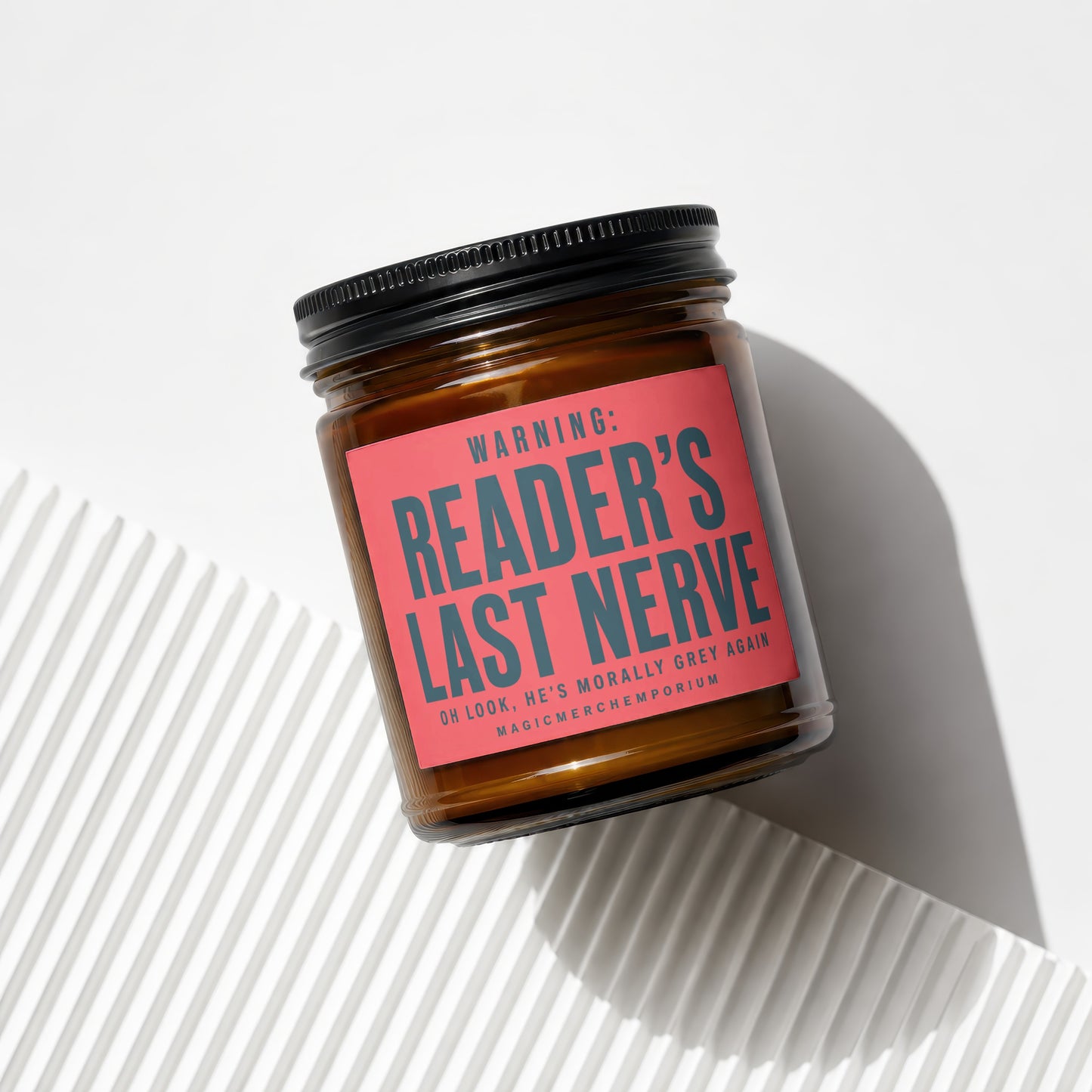 Amber jar candle with black lid and red label reading "Reader's Last Nerve".