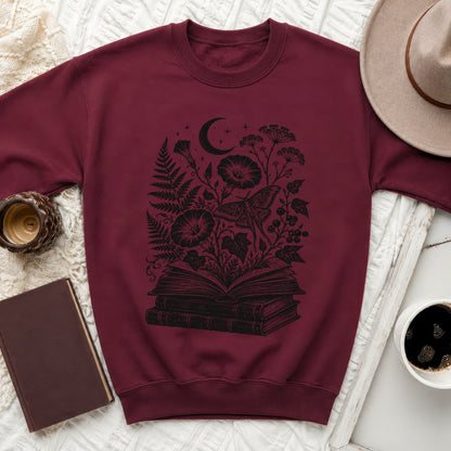 Maroon sweatshirt with black print of open book, moth, moon, and botanical elements.