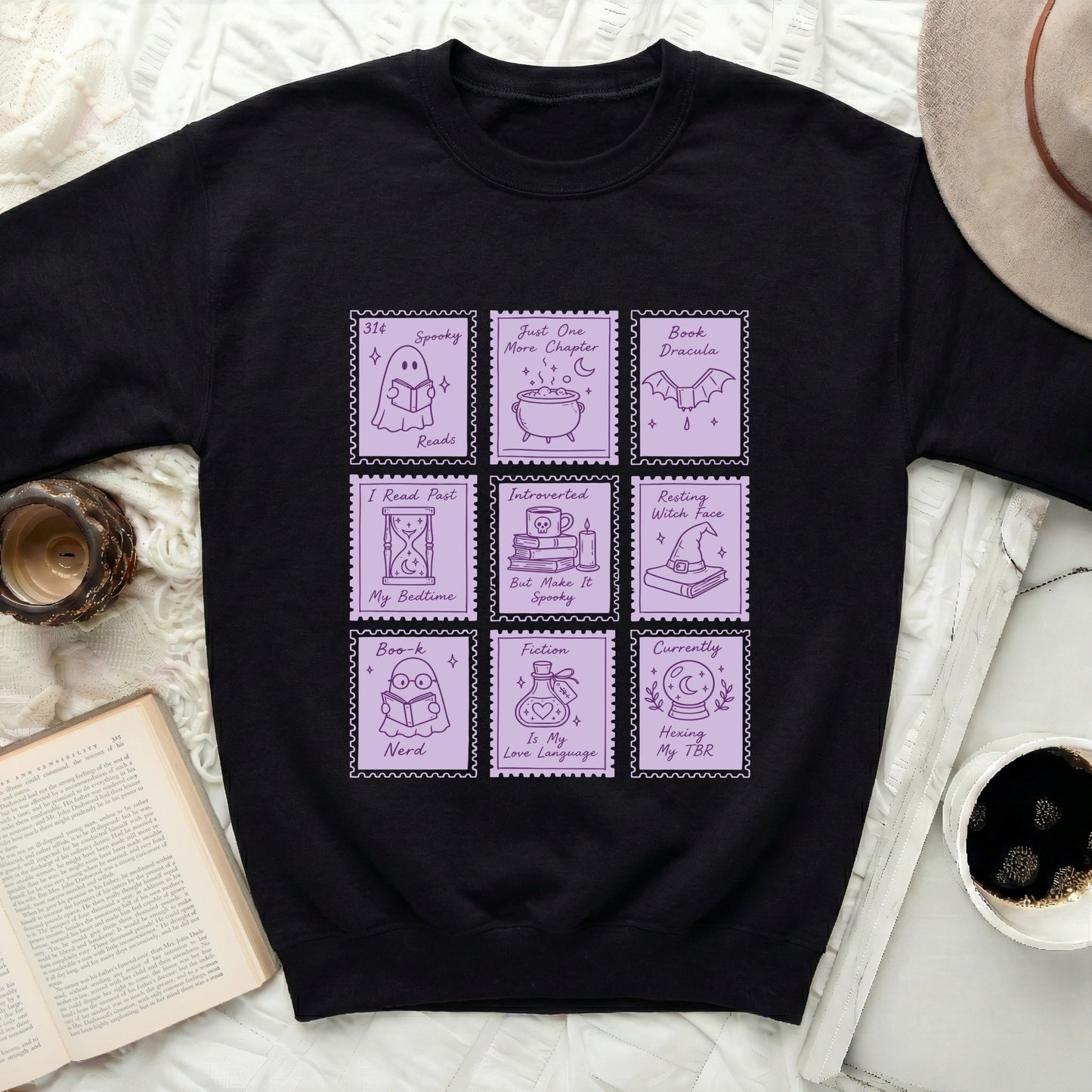 Black sweatshirt with nine pastel purple stamp graphics featuring reading and spooky themes.