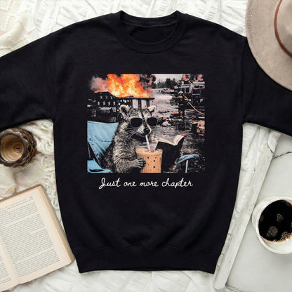 Raccoon in sunglasses sips drink by burning building with text "Just one more chapter".
